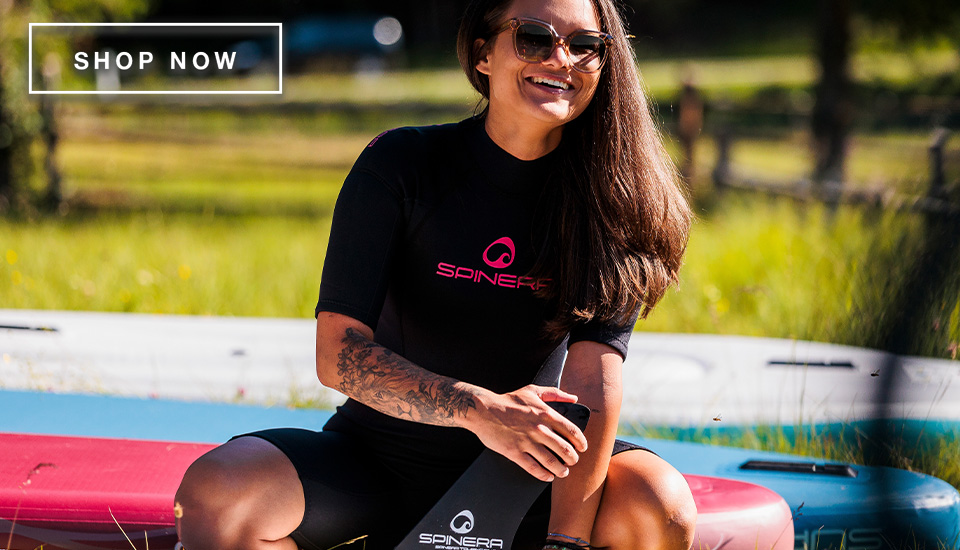 Attraktive Frau mit Neoprenanzug sitzt am SUP Board